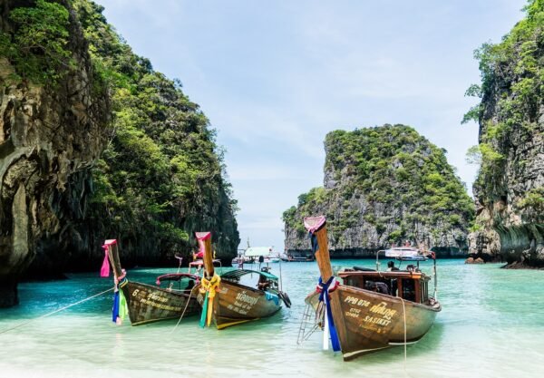 Longtail boats in a turquoise lagoon between limestone cliffs in Thailand
