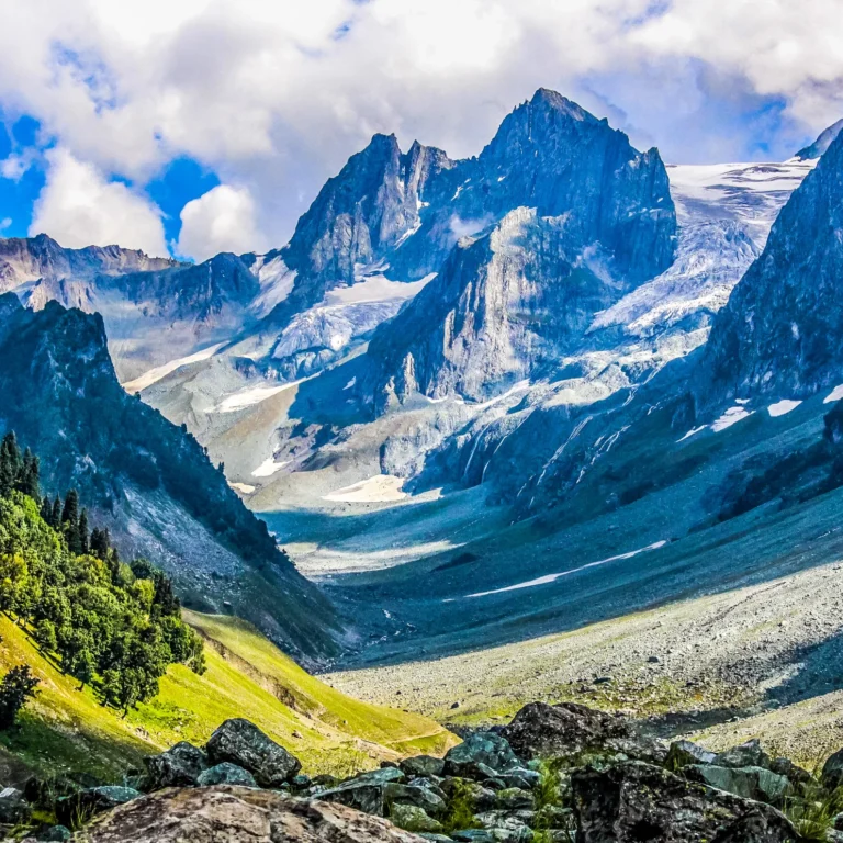 Snow-capped mountain peaks above a green alpine valley in Kashmir
