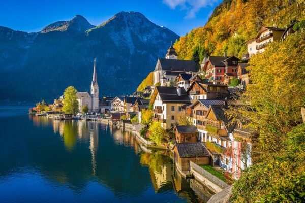Lakeside village with a church spire and autumn hills in Austria