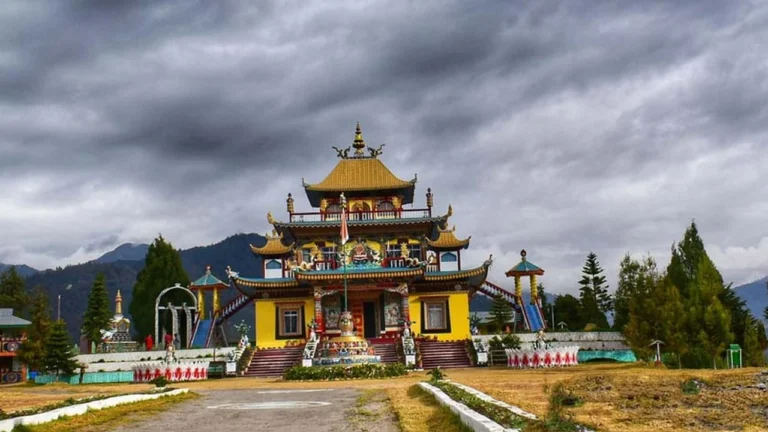 Golden Buddhist monastery with prayer flags under a stormy sky in Tawang