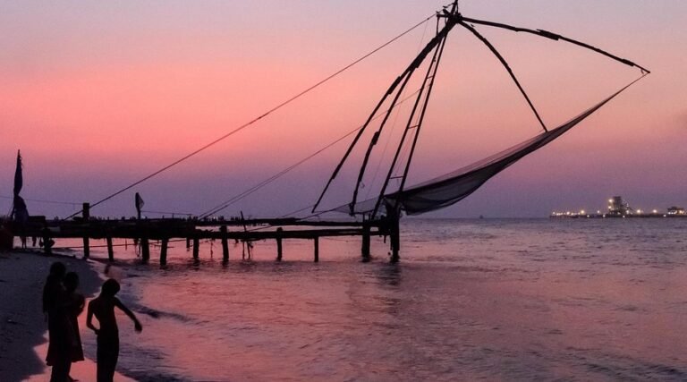 Chinese fishing nets silhouetted against a pink sunset in Kochi, Kerala