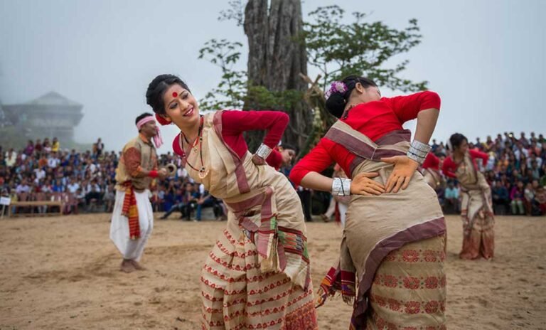 Bihu dancers in traditional Assamese costume performing before a crowd