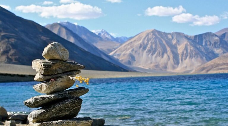 Stacked stones beside a blue Himalayan lake in Ladakh
